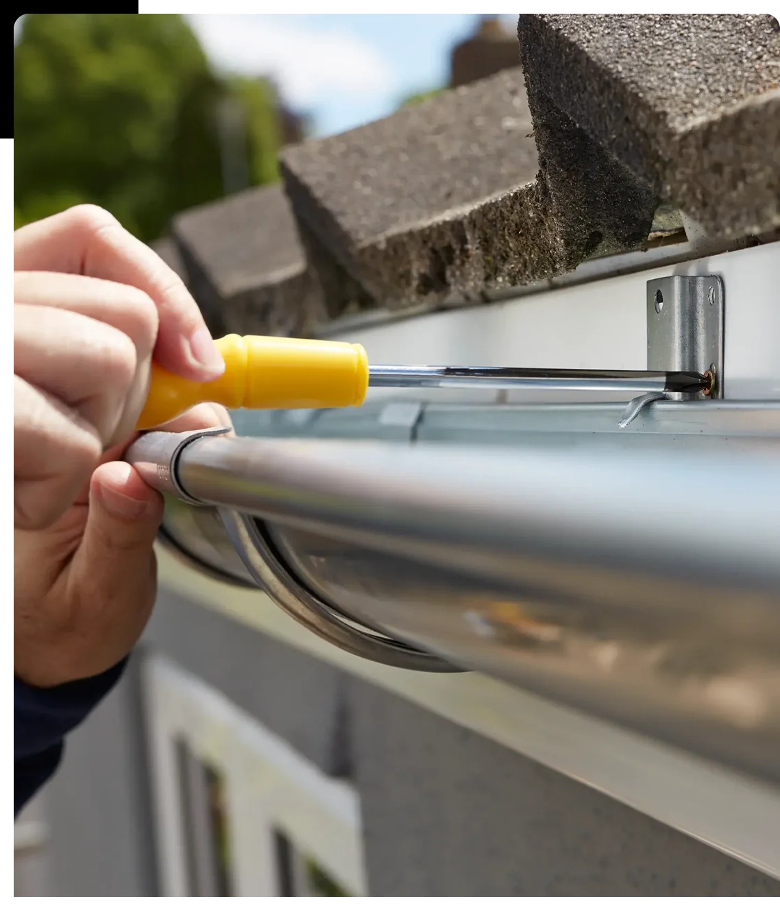 A person holding a yellow object over the top of a gutter.